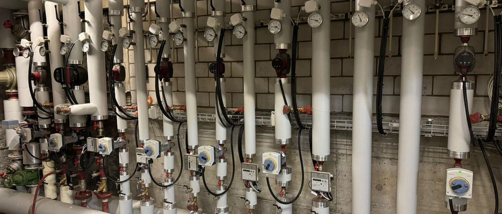 Weiss ummantelter Heizungsverteiler mit Pumpen